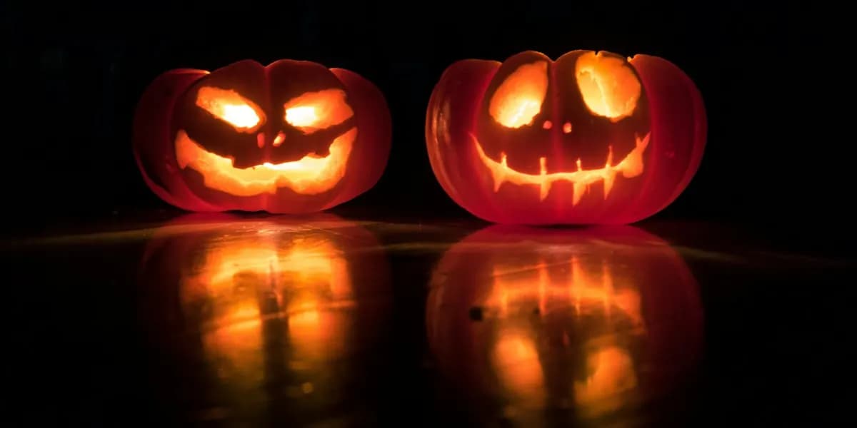 Two glowing jack-o'-lanterns reflected on a dark surface