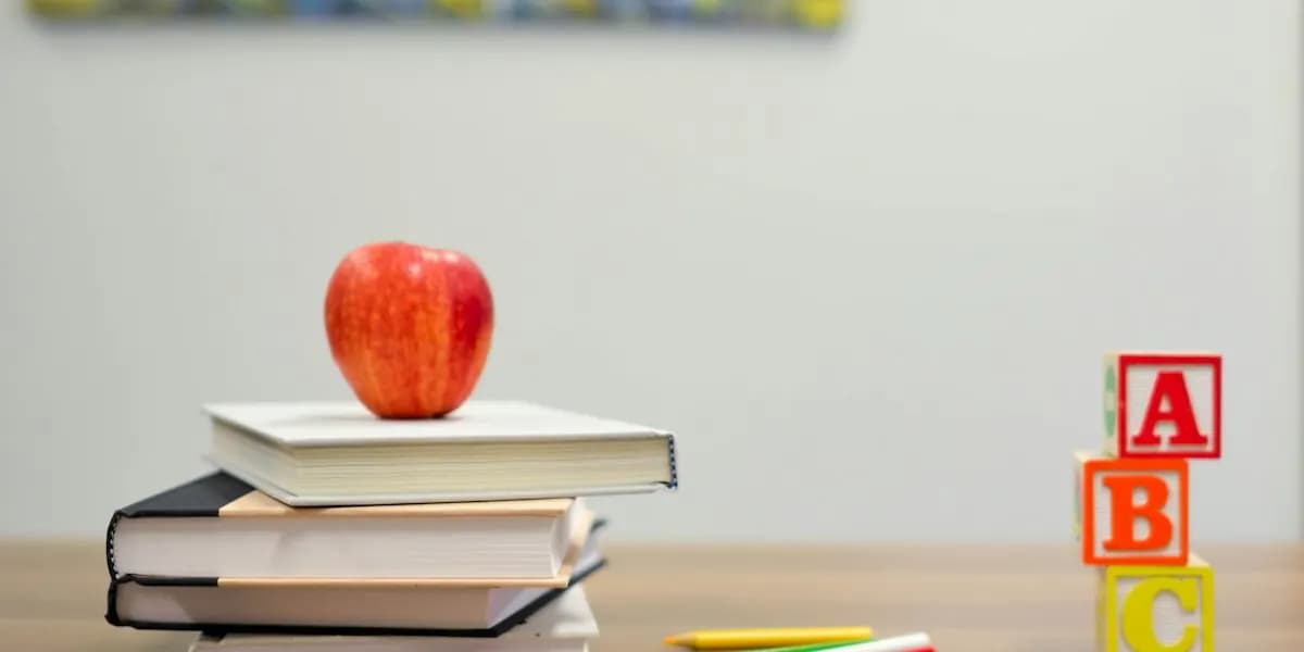 A red apple on a stack of books beside ABC blocks
